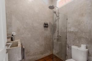 a bathroom with a shower and a toilet and a sink at The Room Padang-Padang in Uluwatu