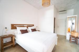 a white bedroom with a large white bed and a table at The Room Padang-Padang in Uluwatu