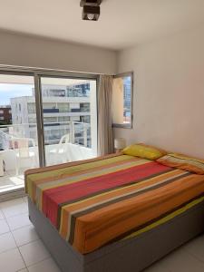 een slaapkamer met een bed en een groot raam bij Apto 3 dormitorios, Punta del Este parada 2 in Punta del Este