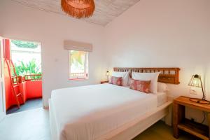 a white bedroom with a large bed and a window at The Room Padang-Padang in Uluwatu