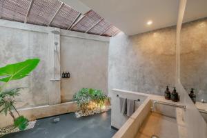 a bathroom with a shower and a tub with plants at The Room Padang-Padang in Uluwatu