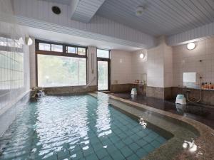 uma casa de banho com uma piscina com uma grande janela em Tabist Nikkokinugawa Onsen Kiyomizu no Yado em Nikko