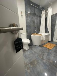 a bathroom with a tub and a toilet and a sink at Modern pool home on the lake near Hardrock FLL airport in Davie