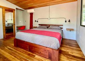 a bedroom with a large bed with a red blanket at Industrial Studio with private Jacuzzi in Uvita