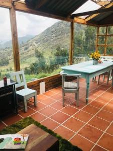 eine abgeschirmte Veranda mit einem Tisch und Stühlen in der Unterkunft Cabaña de descanso en la montaña in Mongua
