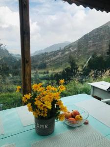 einen Tisch mit einer Vase Blumen und einer Schale Obst in der Unterkunft Cabaña de descanso en la montaña in Mongua
