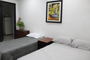 two beds in a room with a picture on the wall at Apartamento 80 O´H Aparthotel. in Ciudad del Este