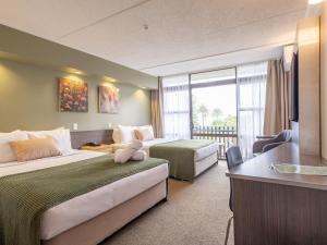 um quarto de hotel com duas camas e uma secretária em Auckland Rose Park Hotel em Auckland