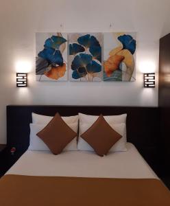 a bedroom with a bed with four paintings on the wall at D Plus B&B Negombo in Negombo