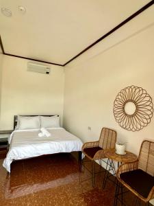 a bedroom with a bed and two chairs at Haven Suites Siargao in General Luna