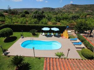 a swimming pool in a yard with chairs and umbrellas at Viila near Syracuse in Siracusa in Siracusa