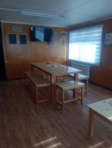 Habitación con mesa, bancos y ventana en Isla yu backpacker, en Puerto Natales