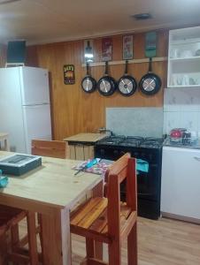 La cuisine est équipée d'une table, d'une cuisinière et d'un réfrigérateur. dans l'établissement Isla yu backpacker, à Puerto Natales