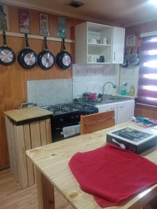 cocina con fogones y mesa de madera en Isla yu backpacker, en Puerto Natales