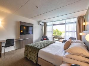 a hotel room with a bed and a television at Auckland Rose Park Hotel in Auckland