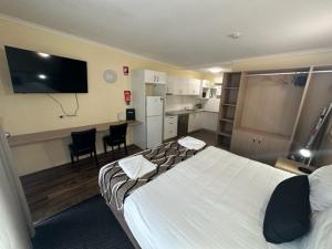 a hotel room with a large bed and a kitchen at City Centre Motel Kempsey in Kempsey