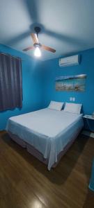 a blue bedroom with a bed and a ceiling fan at Vila Nina in São Miguel do Gostoso