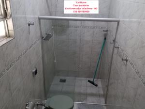 a bathroom with a shower with a toilet and a sign at LM Home 1 - casa com 2 quartos in Governador Valadares