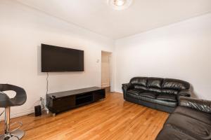 a living room with a leather couch and a flat screen tv at 3 bedroom apartment in Verdun in Montreal