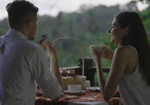 un homme et une femme assis à une table avec une tasse de café dans l'établissement Kayumanis Ubud Private Villas & Spa, à Ubud
