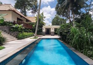 a swimming pool in front of a house at Kayumanis Ubud Private Villas & Spa in Ubud