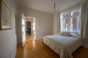 a white bedroom with a bed and a window at Pignon sur Parc in Trois-Rivières