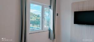 a room with a window and a flat screen tv at Pousada Roberto Monteiro - Frente Mar in Florianópolis