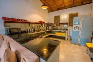 a large kitchen with a counter and a refrigerator at Sixth Sense Hostel in Galle