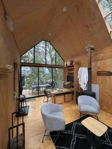ein Wohnzimmer mit zwei Stühlen und einem Tisch in der Unterkunft Acogedora cabaña con tinaja libre para disfrutar y Home Office para teletrabajar in Las Trancas