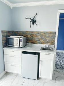 a white kitchen with a microwave and a sink at Casa Agora in St Petersburg
