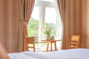 a bedroom with a table and a window with a plant on it at H Flower Hotel and Villa Đà Lạt in Da Lat