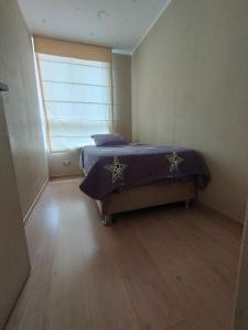 a bedroom with a bed with a purple comforter and a window at Hermoso condominio estilo Urban in Lima