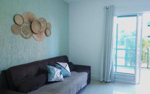 uma sala de estar com um sofá e chapéus de palha na parede em Golden Lake RJ - Lindo como um Resort! em Arraial do Cabo
