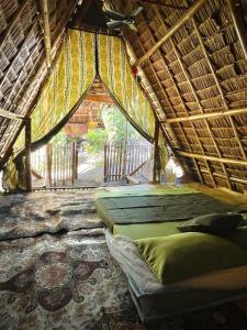a bedroom with two beds and a thatched roof at Tribal Huts Community in Daanbantayan
