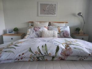 a bed with a floral comforter and pillows at Anchor watch in Whangamata