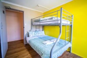 a bedroom with a bunk bed and a yellow wall at The Hostel, Airlie Beach in Airlie Beach