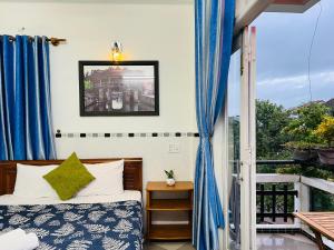 1 dormitorio con 1 cama y una ventana con cortinas azules en Phuc Bao Center Local Homestay - 3 mins walk to Old Town en Hoi An