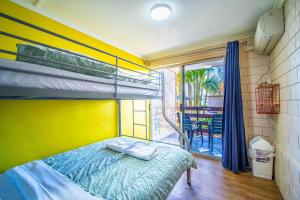 a bedroom with a bunk bed and a balcony at The Hostel, Airlie Beach in Airlie Beach