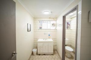 a white bathroom with a sink and a toilet at The Hostel, Airlie Beach in Airlie Beach