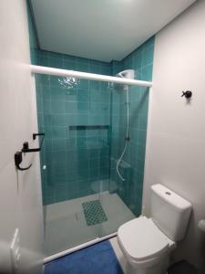 a bathroom with a shower with a toilet and green tiles at Cobertura Vista Para o Mar Praia Boraceia-SP Litoral Norte in Boracéia