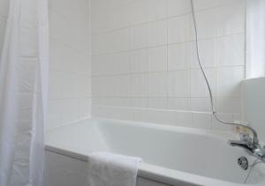 a white bathroom with a bath tub with a towel at Prime London Location 3-Bed Flat in London