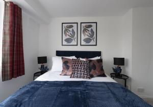 sypialnia z łóżkiem z niebieskim kocem i poduszkami w obiekcie Prime London Location 3-Bed Flat w Londynie