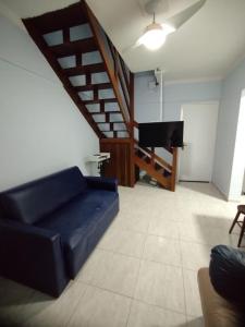 a living room with a blue couch and a piano at Cobertura Vista Para o Mar Praia Boraceia-SP Litoral Norte in Boracéia