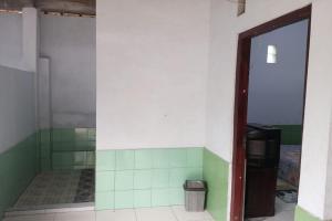 a bathroom with green and white tiled walls and a mirror at Homestay Wijaya Mulya in Magelang