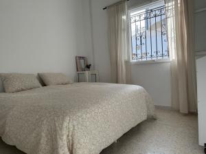 a white bedroom with a bed and a window at Dar almasyaf, maison bord de mer in Gabès