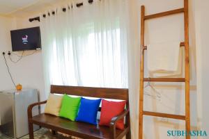 un banc avec des oreillers colorés assis devant une fenêtre dans l'établissement Subhasha Summer House, à Talalla South