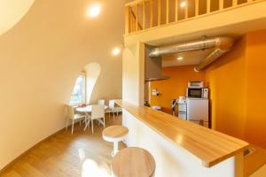 a kitchen and dining room with orange walls and wooden floors at Cam Cam Dome House & SAUNA 豊岡海岸 in Minamiboso