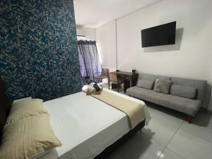 1 dormitorio con cama, sofá y TV en Hermoso Departamento en Condominio Céntrico Con piscina!, en Trinidad