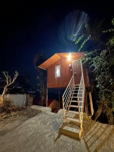 a house with a staircase in front of it at night at TREE HOUSE BY THE CITY ESCAPE in Shimla