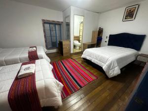 Un dormitorio con dos camas y una alfombra. en AITANA'S HOUSE - SAN BLAs, en Cusco